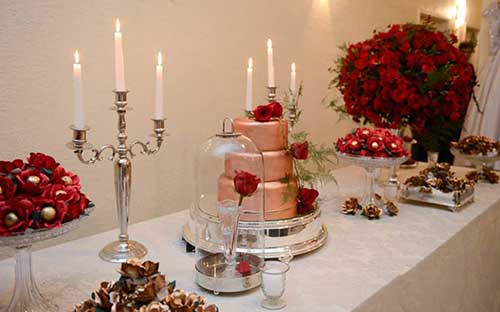 mesa de bolo dourado com flores vermelhas