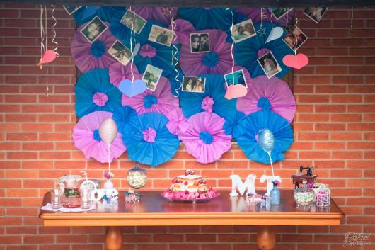 mesa de bolo com detalhes ao fundo rosa e azul com fotos