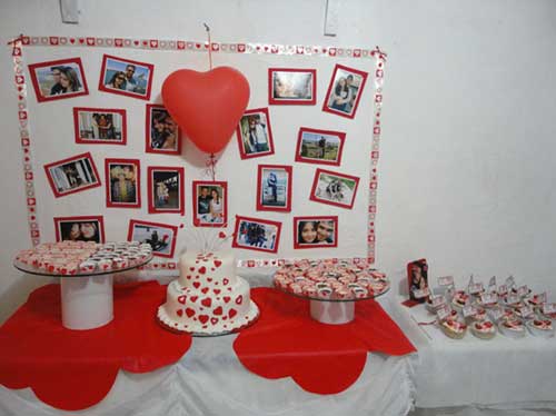 mesa de bolo vermelha e branca com fotos ao fundo