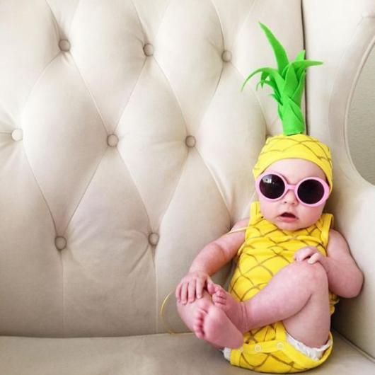 Bebê vestido de abacaxi, com óculos de sol.