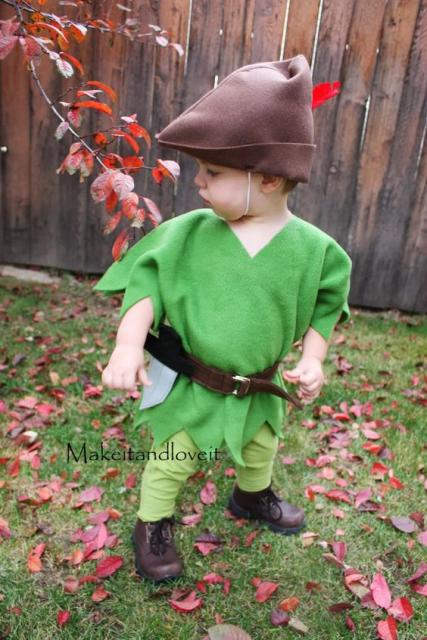 Menino vestido de Peter Pan, com roupa verde e touca marrom.