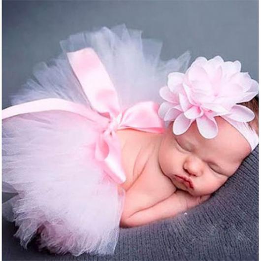 Bebê dormindo com adereço rosa na cabeça e saia de tutu rosa.