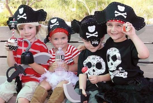 Quatro crianças vestidas de piratas, com roupas pretas e vermelhas.