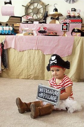 Menina vestida de pirata, com saia, blusa listrada e chapéu.
