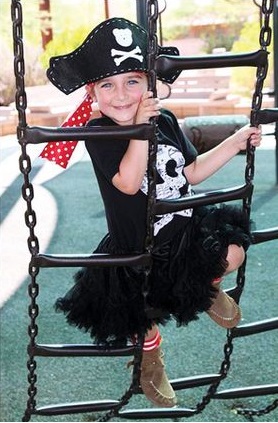 Menina vestida de pirata com blusa e saia pretas e chapéu.