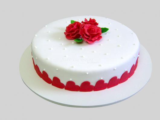 Decoração simples de aniversário com bolo branco e flores vermelhas 