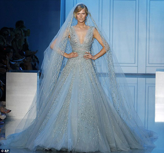 Modelo usa vestido de noiva longo na cor azul claro ao fundo de mangas de renda.