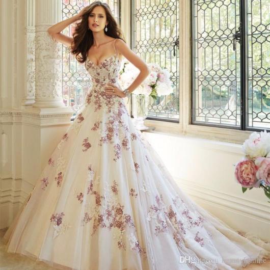 Modelo usa vestido branco longo, tomara que caia com flores cor de rosa em toda peça.