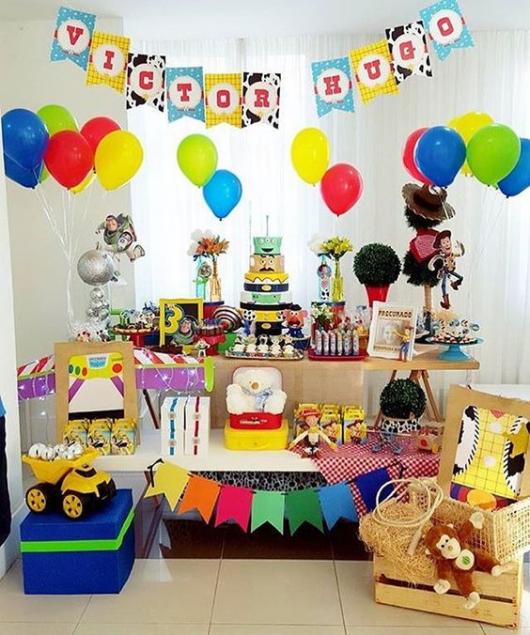 Festa Toy Story decorada com caixote de madeira, palha decorativa, varal de bandeirinhas e bonecos do filme