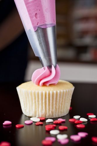 Cupcake sendo decorado com cobertura de morango.