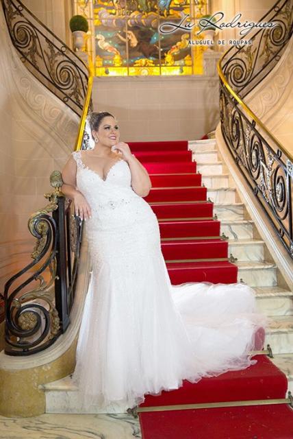 Mulher com vestido branco em escadaria.