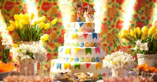 Decoração de Festa Junina Infantil com arranjos de flores e bolo decorado com bandeirinhas