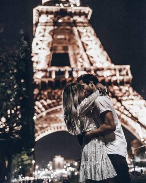 Foto de casal se beijando em frente à Torre Eiffel.
