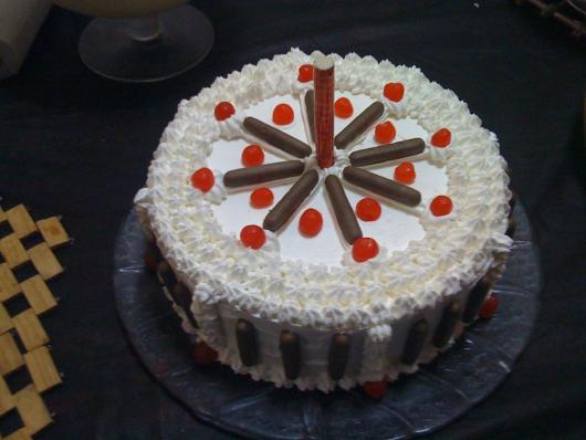 Um bolo redondo com chantilly e chocolate, uma combinação clássica que todos adoram