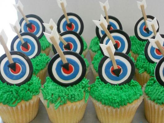 Cupcakes decorados com enfeite de alvo e flecha.