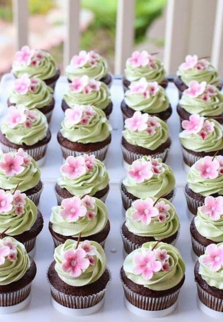 Cupcakes com glacê verde e flores rosas.