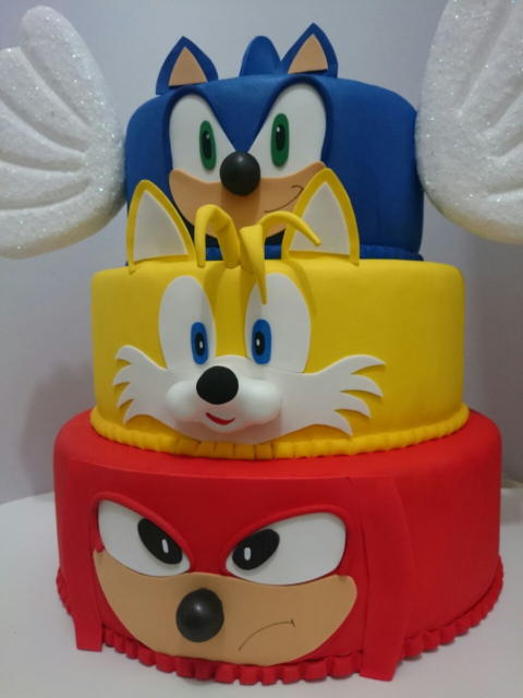 Um bolo de três andares que destaca o Sonic, o Miles e o Knuckles