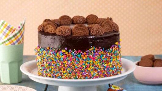 Ideia de bolo decorado com confeitos coloridos e biscoitos de chocolate