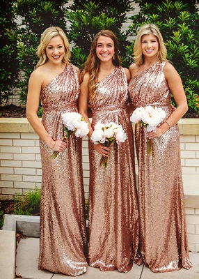 Três madrinhas com vestido rosê gold de um ombro só.