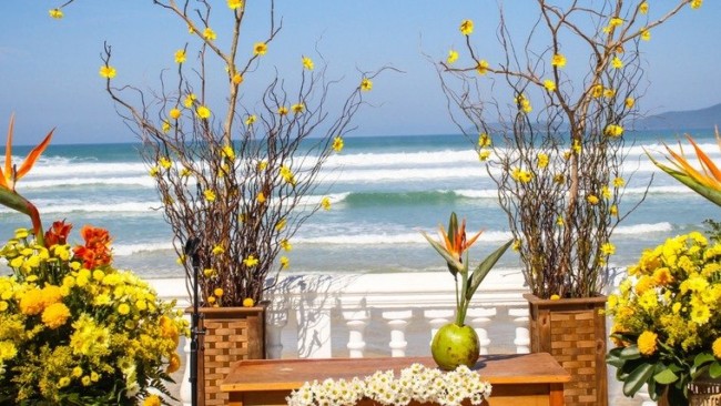 Flores amarelas e galhos em casamento na praia
