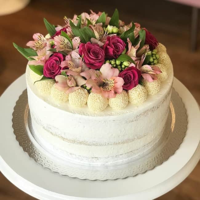 Decoração de bolo de noivado simples com doces e flores